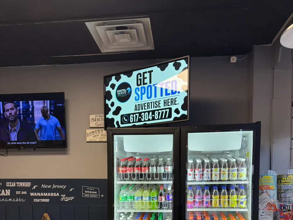 Wall-mounted Digital Wave screen above the drink coolers in an Ocean Township bagel shop